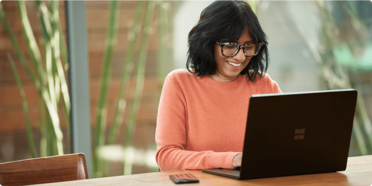 A woman working in a casual office environment, smiling to herself.